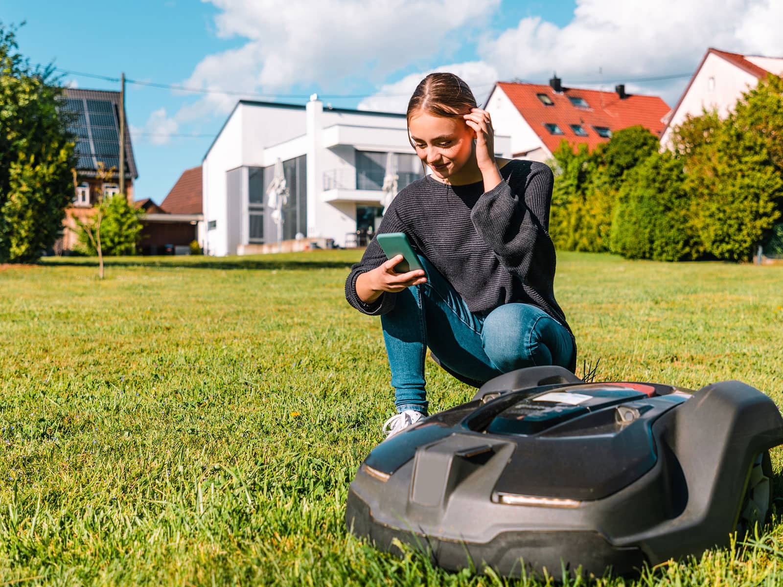 Ung pige er ved at starte en robotplæneklipper. Men hvad koster en robotplæneklipper i strøm?