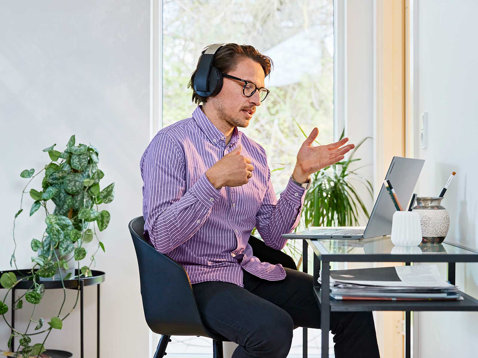 Mand sidder ved skrivebord med pc i online møde. 