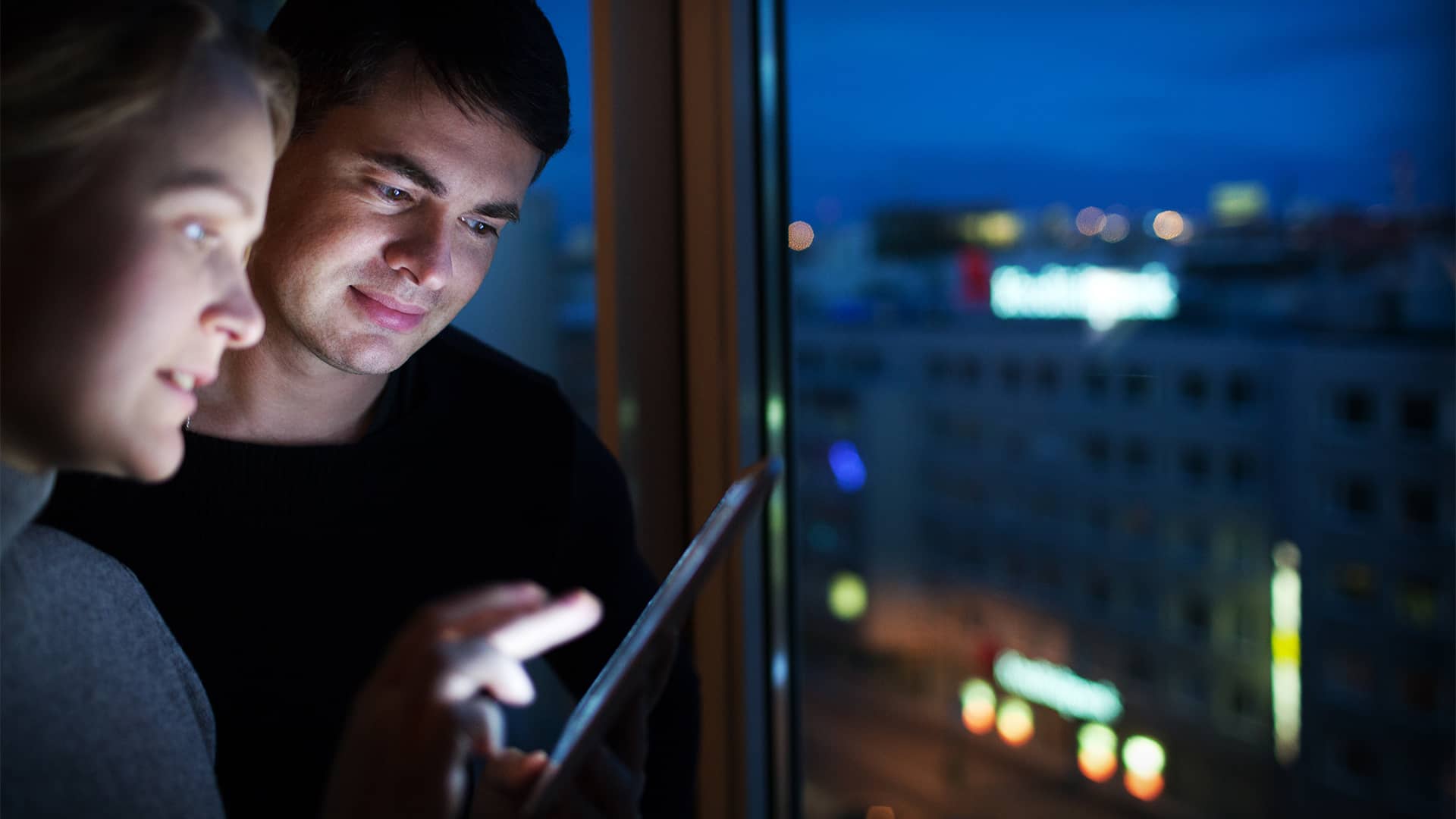 Par står med ipad om aftenen