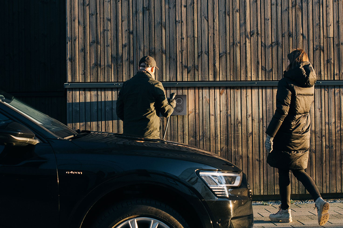 Mand og kvinde oplader elbil med ladestander fra EWII. Ved at lade elbilen op om natten opnår du typisk en besparelse på din elregning og på dit CO2 aftryk.