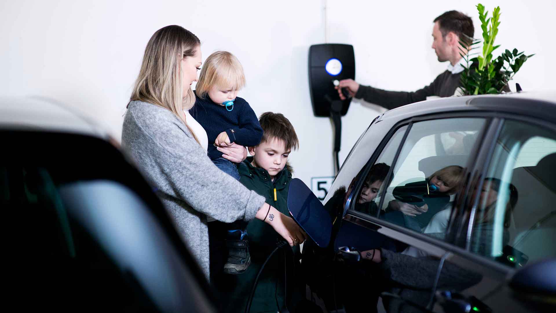 Familie oplader deres elbil med en ladeboks med refusion fra EWII. Med en ladeboks med serviceaftale kan du få automatisk elafgiftsrefusion. Bestil egen ladeboks med refusion her.