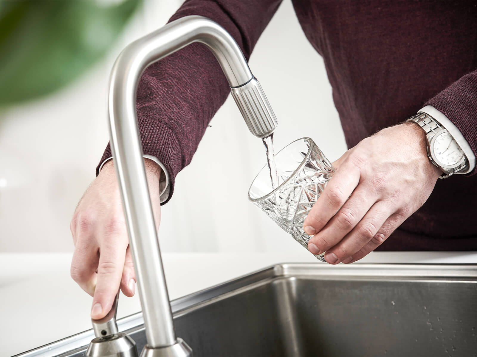 Hælder vand i glas ved vandhane