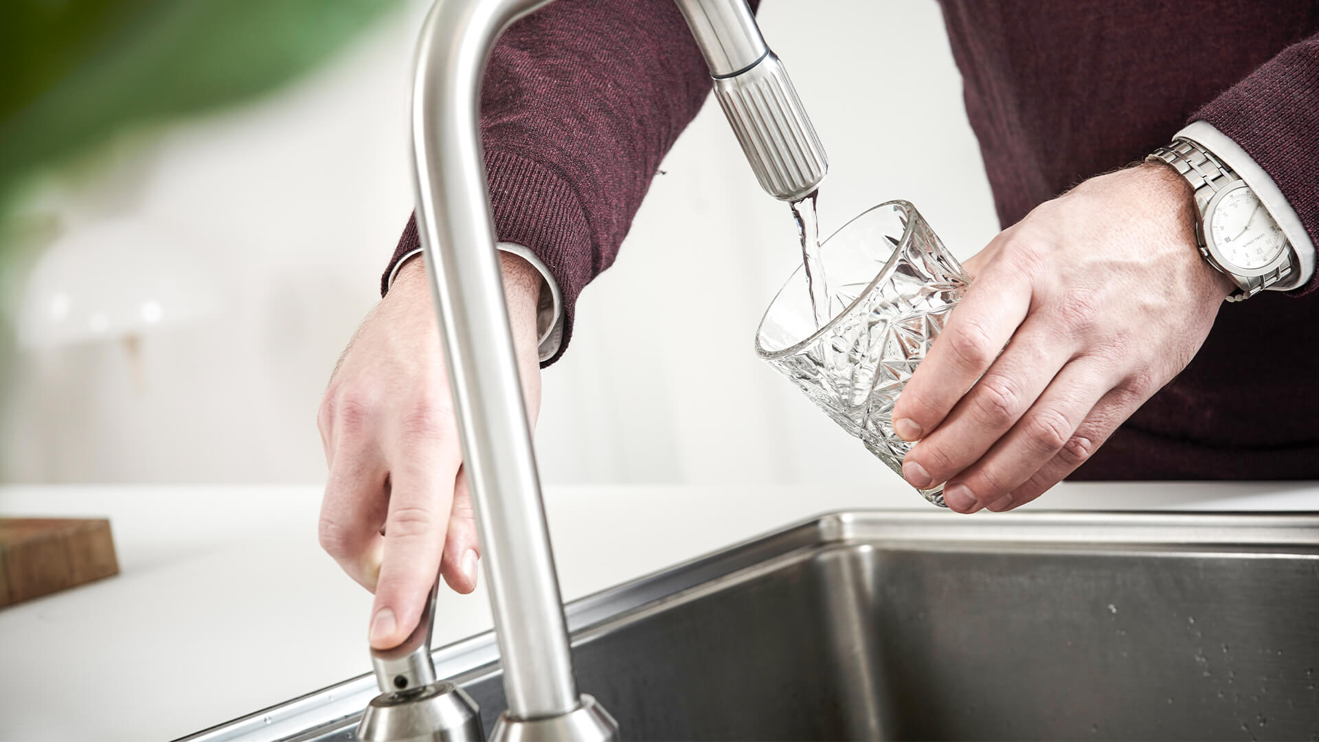 Hælder vand i glas ved vandhanen