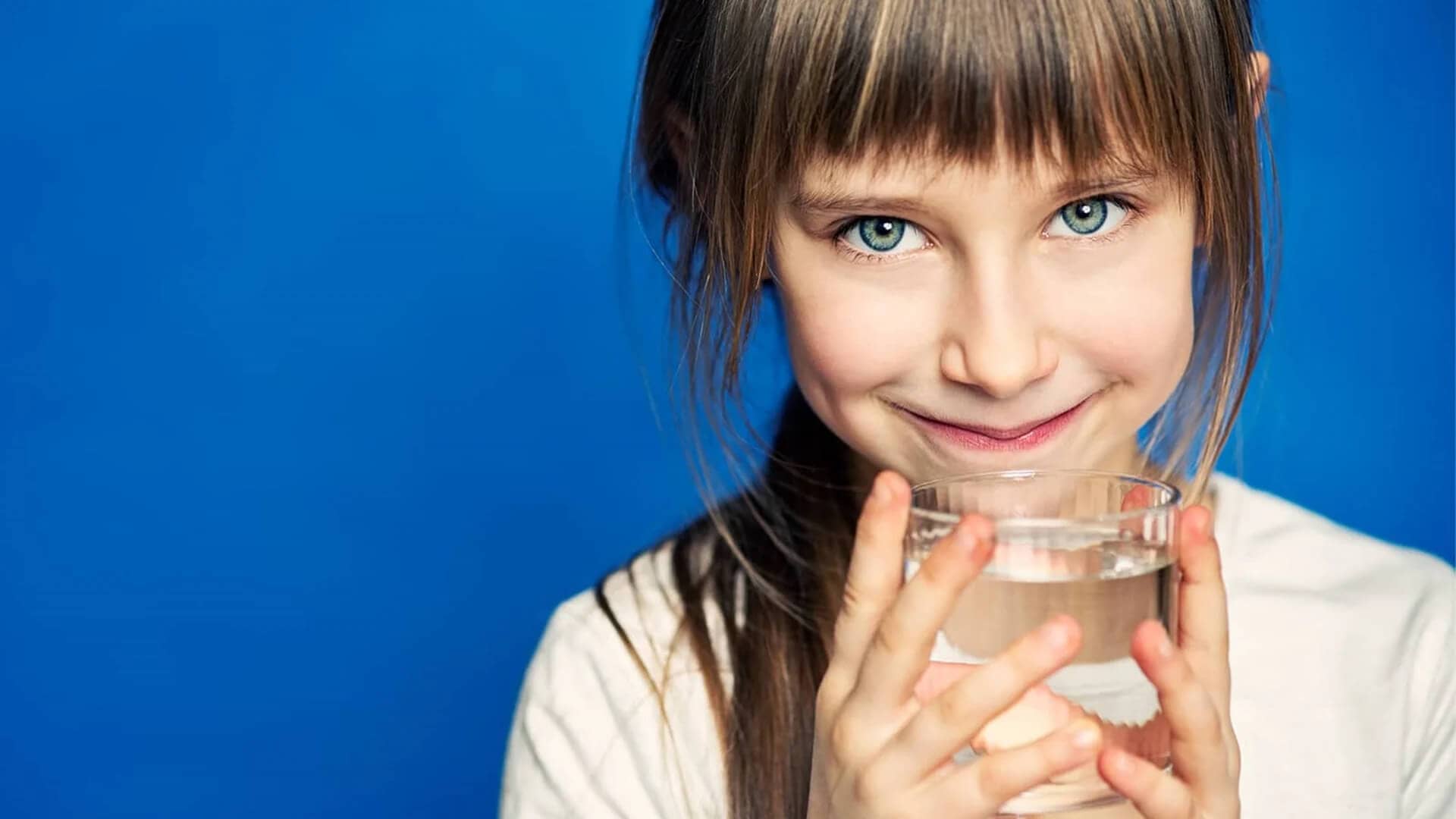 Pige der står med et glas vand i hænderne og smiler uden bekymring for, om der er nok rent drikkevand i fremtiden. Læs om rent drikkevand i Danmark og rent drikkevand i verden.