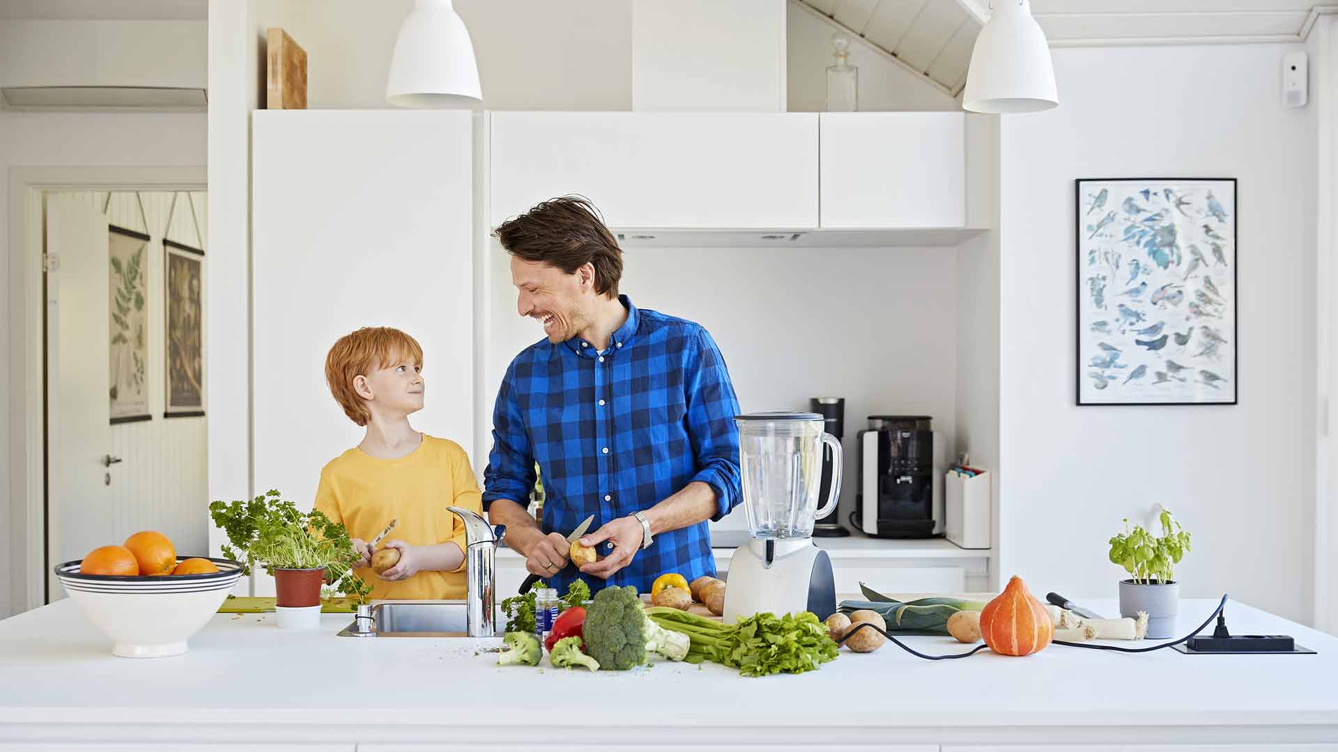 Far og søn i køkkenet, hvor moderne teknologi hjælper med at blive mere bæredygtig.