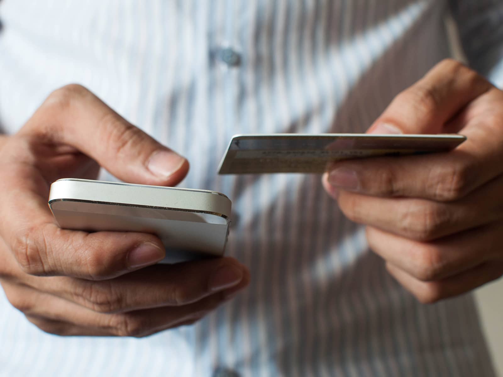 Telefon og kreditkort i hånden. Forklaring på forskel af forfalden og ikke forfalden saldo