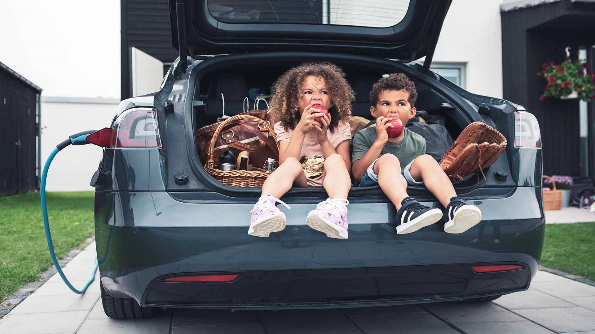 To børn spiser æbler, mens de sidder i bagagerummet på en Tesla, der lader. Men hvad koster det at lade en Tesla? Det undersøger vi her.